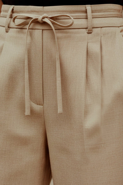 Pantalón de fit wide leg, cintura alta con pretina, trabillas y lazo amarrable, pinzas frontales y bolsillos delanteros. Cierre frontal con broche y cremallera ocultos. Detalle de doblez en bajo.