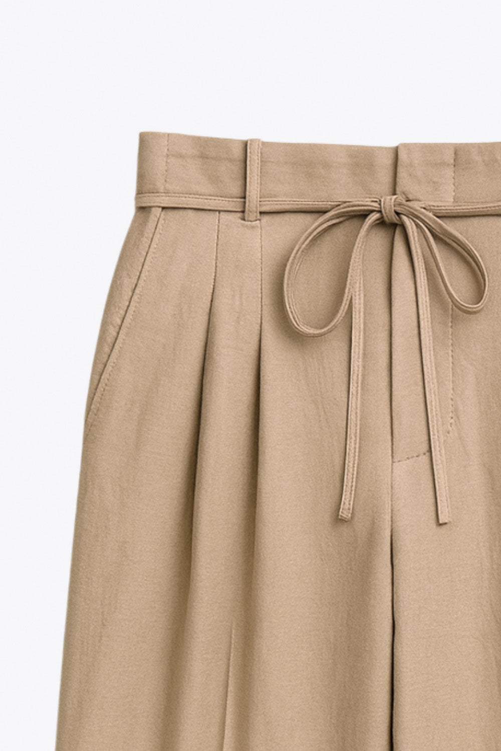 Pantalón de fit wide leg, cintura alta con pretina, trabillas y lazo amarrable, pinzas frontales y bolsillos delanteros. Cierre frontal con broche y cremallera ocultos. Detalle de doblez en bajo.