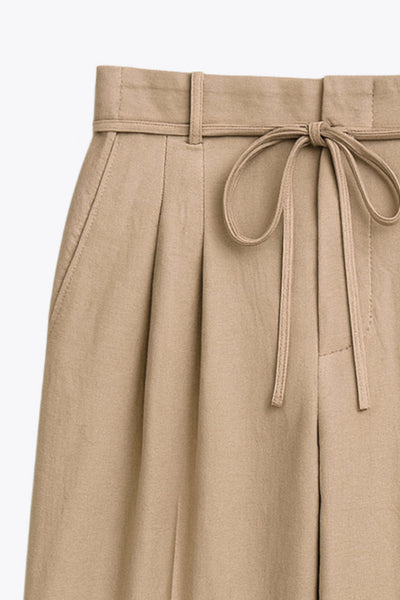 Pantalón de fit wide leg, cintura alta con pretina, trabillas y lazo amarrable, pinzas frontales y bolsillos delanteros. Cierre frontal con broche y cremallera ocultos. Detalle de doblez en bajo.