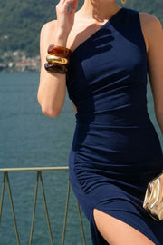 Vestido midi asimétrico de un hombro, fit ajustado, escote diagonal, sin mangas, plisado en costados, abertura lateral en bajo y cut out en espalda. Cierre posterior con cremallera oculta.