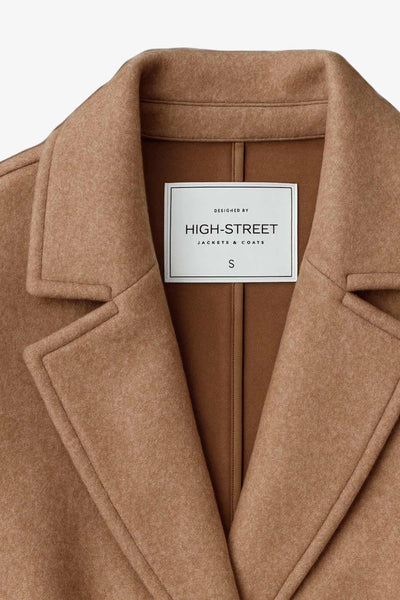 Abrigo largo de manga larga, con solapa, bolsillos delanteros de parche, trabillas y cinturón amarrable del mismo tejido.