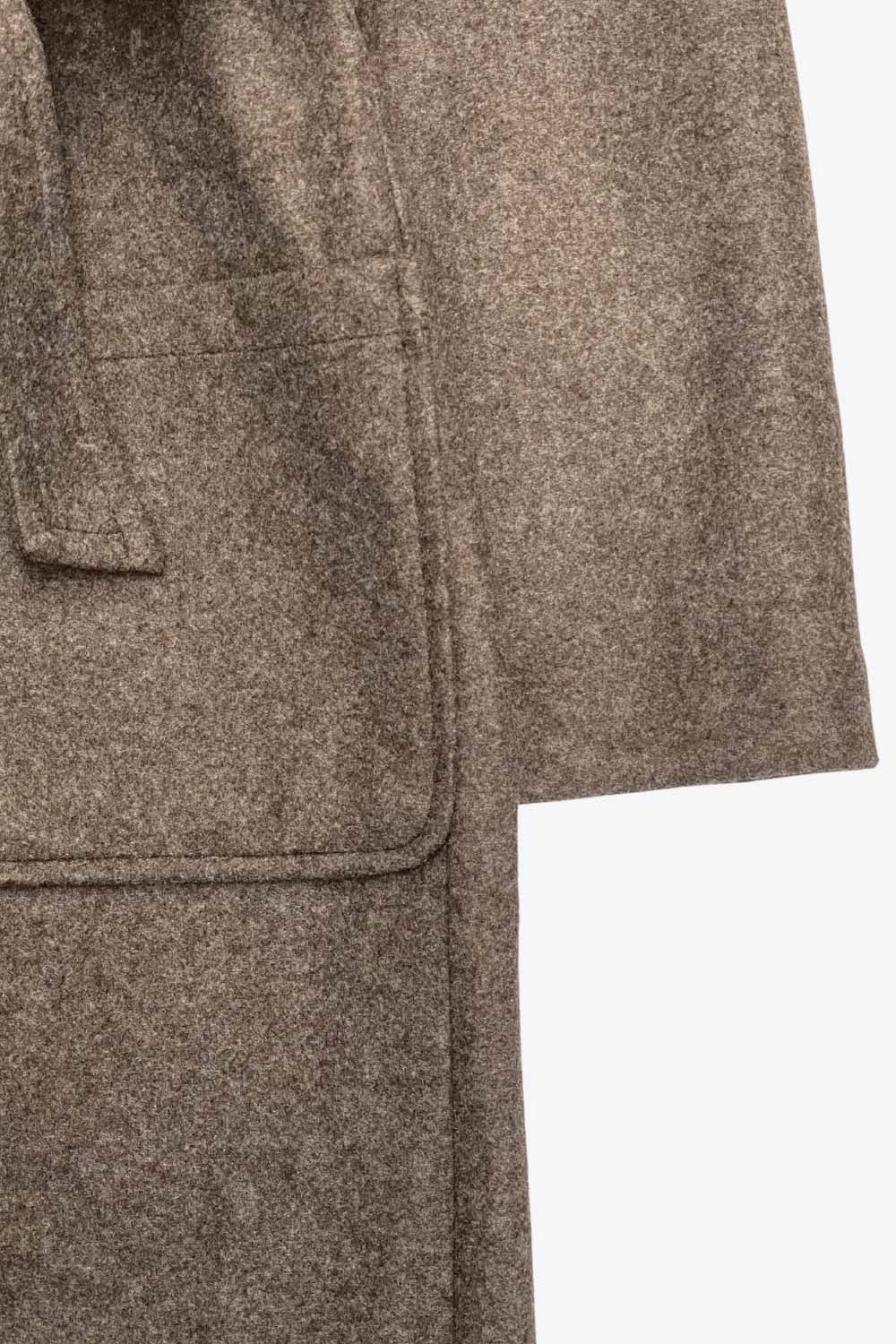 Abrigo largo de manga larga, con solapa, bolsillos delanteros de parche, trabillas y cinturón amarrable del mismo tejido.