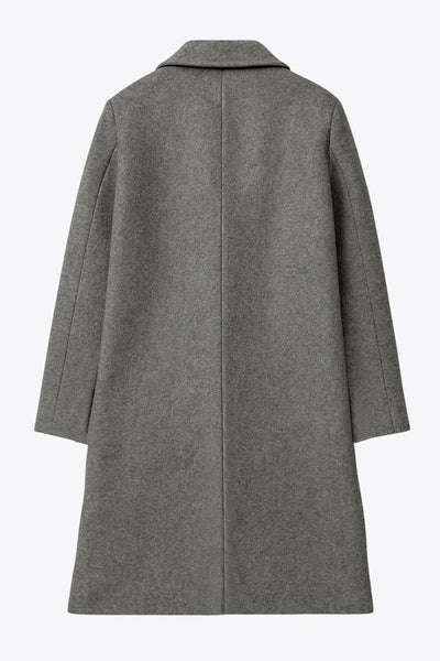 Abrigo largo de fit recto, con solapa y hombreras, manga larga y bolsillos frontales con vivos y cierre frontal con botón en contraste.