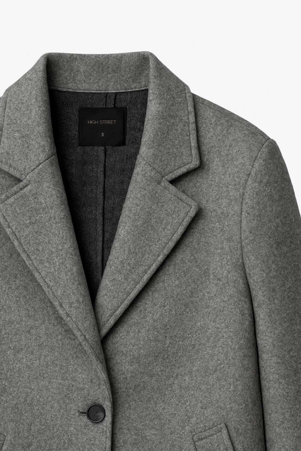 Abrigo largo de fit recto, con solapa y hombreras, manga larga y bolsillos frontales con vivos y cierre frontal con botón en contraste.