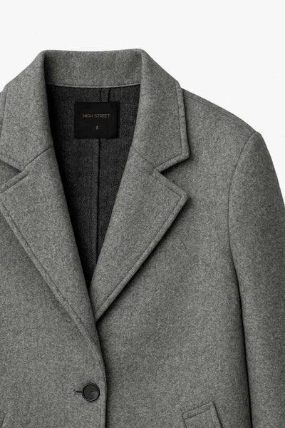 Abrigo largo de fit recto, con solapa y hombreras, manga larga y bolsillos frontales con vivos y cierre frontal con botón en contraste.