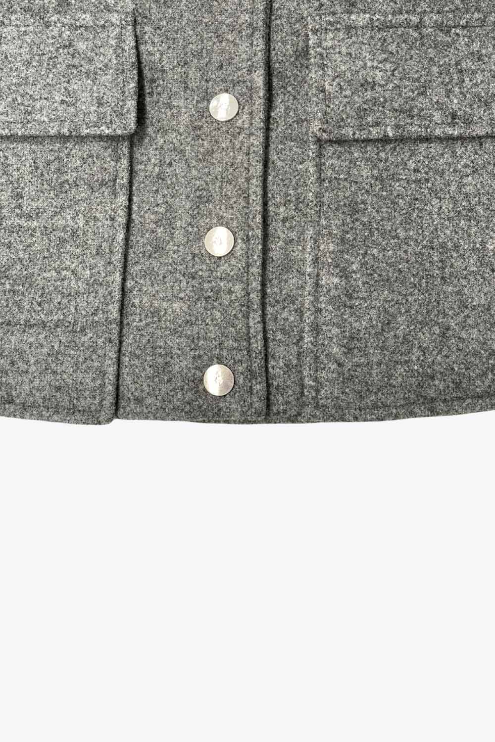 Abrigo corto de fit recto, manga larga, cuello solapa, bolsillos delanteros de parche con cartera y cierre frontal con hilera de botones en contraste.