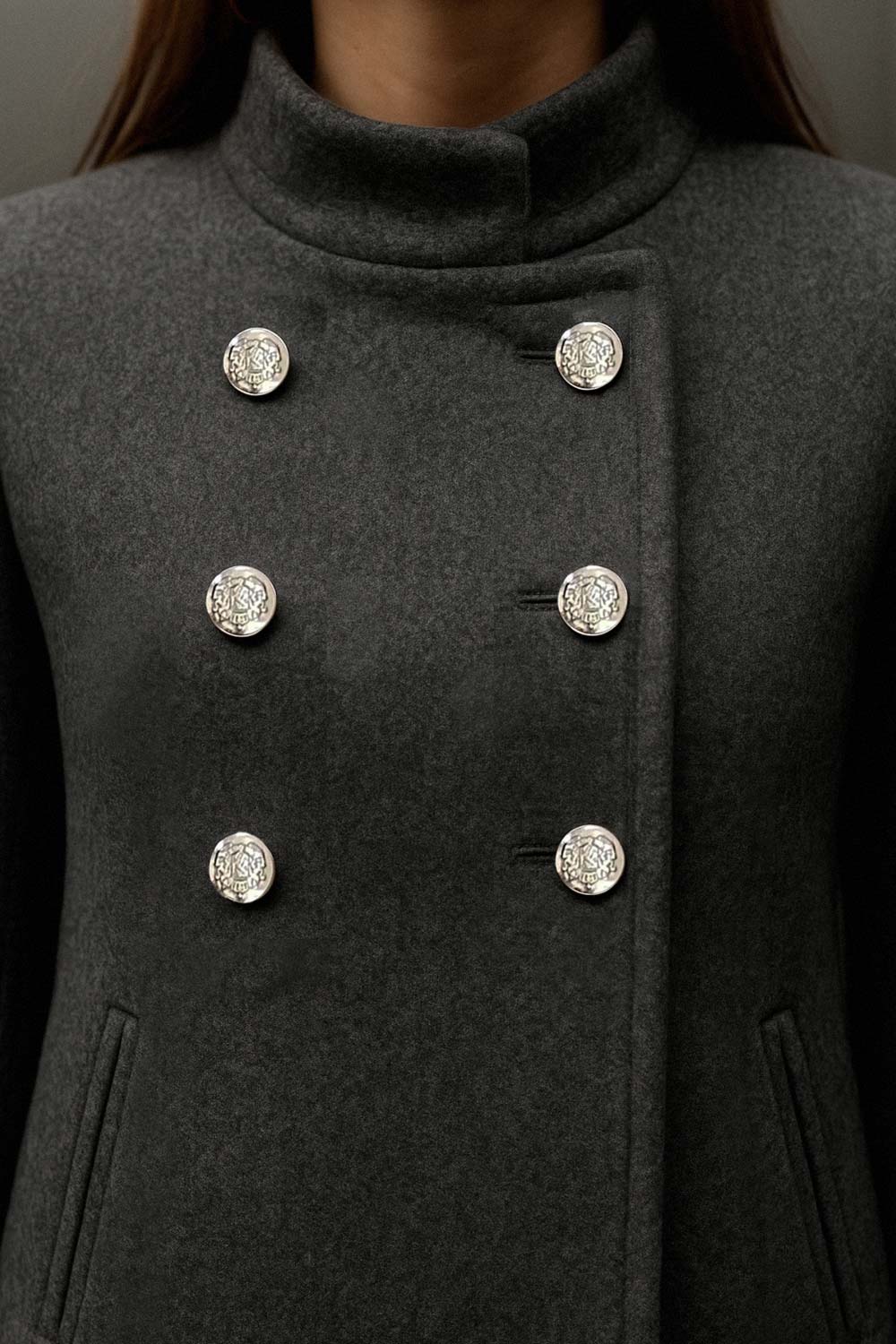 Abrigo cruzado de cuello alto, bolsillos delanteros y manga larga. Cierre frontal con doble cruce de botones en contraste.