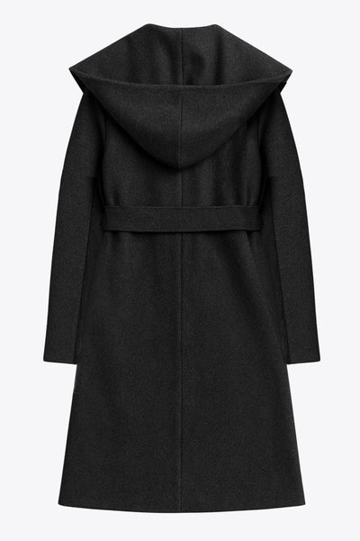 Abrigo largo de fit recto con capucha, manga larga y bolsillos delanteros. Detalle de trabillas y cinturón amarrable del mismo tejido.