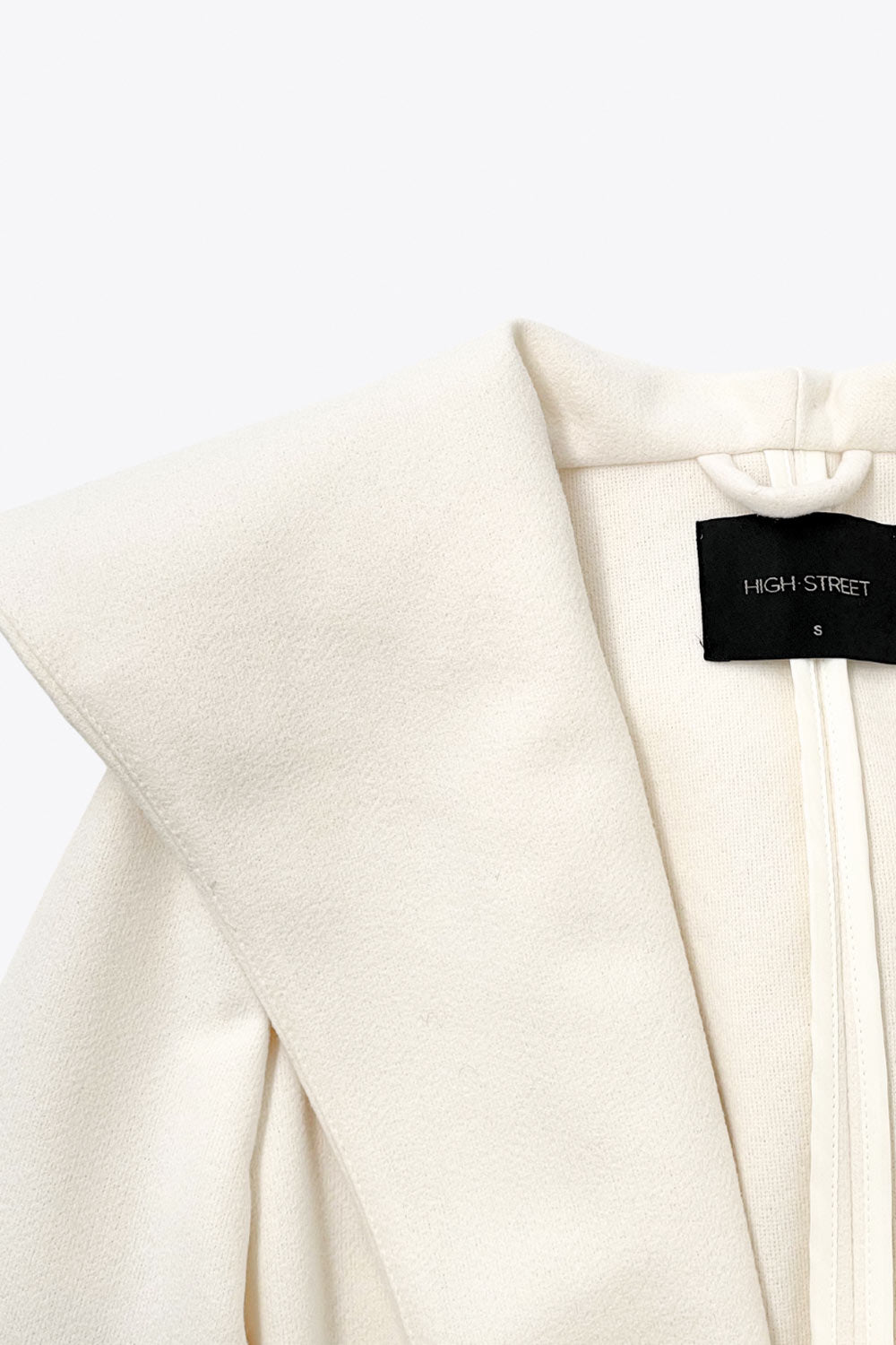 Abrigo largo de fit recto con capucha, manga larga y bolsillos delanteros. Detalle de trabillas y cinturón amarrable del mismo tejido.