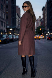 Abrigo largo de fit recto con solapa, manga larga con puños abotonados y bolsillos delanteros con vivos. Cierre frontal con doble cruce de botones. Detalle de abetura posterior en bajo, trabillas y cinturón amarrable del mismo tejido.