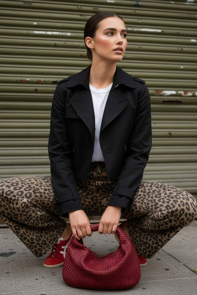 Abrigo trench corto de fit recto, cuello solapa, manga larga, trabillas con botón en puños y hombros. Bolsillos delanteros con vivos y cierre frontal con doble cruce de botones.