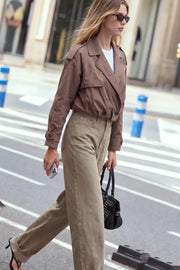 Abrigo trench corto de fit abullonado, cuello solapa, manga larga con trabillas con botón en puños y hombros. Detalle de bata decorativa frontal y cierre con doble cruce de botón en contraste. Detalle de plisados en bajo.