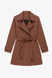 Abrigo trench corto de fit recto, con cuello solapa, bolsillos delanteros con vivos, detalle de bata trasera y manga larga. Trabillas, cinturón amarrable del mismo tejido y cierre frontal con doble cruce de botones en contraste. Detalle de trabilla y botón en hombros, bata trasera, cuello y puños.