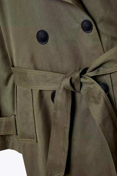 Abrigo trench corto de fit recto, con cuello solapa, bolsillos delanteros con vivos, detalle de bata trasera y manga larga. Trabillas, cinturón amarrable del mismo tejido y cierre frontal con doble cruce de botones en contraste. Detalle de trabilla y botón en hombros, bata trasera, cuello y puños.