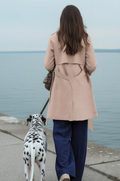 Abrigo trench corto de fit recto, con solapa, bolsillos delanteros con vivos, detalle de bata frontal con botón decorativo y trasera. Manga larga con trabilla en puños, cinturón amarrable del mismo tejido y cierre frontal con doble cruce de botones en contraste.