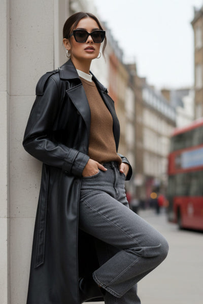 Abrigo trench de efecto piel, fit recto, con solapa, bolsillos delanteros con vivos, abertura posterior en bajo, bata trasera y manga larga. Cinturón amarrable del mismo tejido y cierre frontal con doble cruce de botones. Detalle de trabilla y botón en hombros y puños.