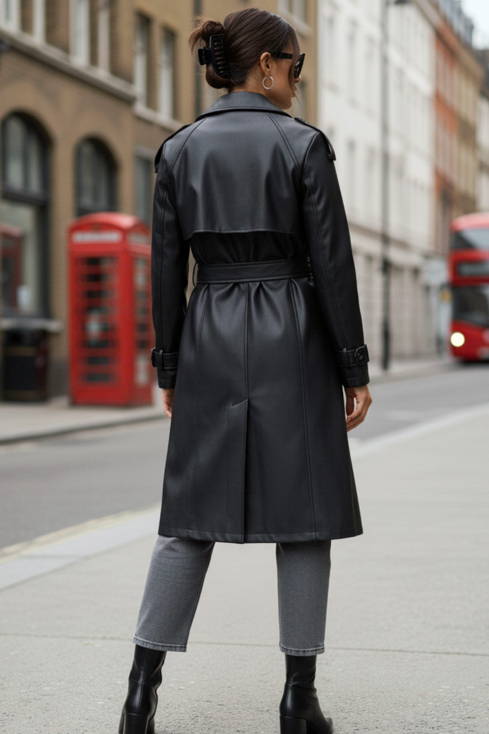 Abrigo trench de efecto piel, fit recto, con solapa, bolsillos delanteros con vivos, abertura posterior en bajo, bata trasera y manga larga. Cinturón amarrable del mismo tejido y cierre frontal con doble cruce de botones. Detalle de trabilla y botón en hombros y puños.