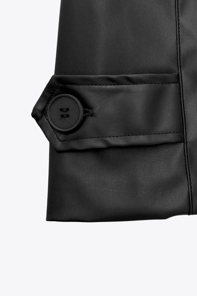 Abrigo trench de efecto piel, fit recto, con solapa, bolsillos delanteros con vivos, abertura posterior en bajo, bata trasera y manga larga. Cinturón amarrable del mismo tejido y cierre frontal con doble cruce de botones. Detalle de trabilla y botón en hombros y puños.