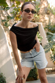 Bermuda corta de denim, fit recto, cintura media con pretina y trabillas, bolsillos delanteros y traseros de parche. Cierre frontal con botón y cremallera oculta. Detalle de rotos en bajo.