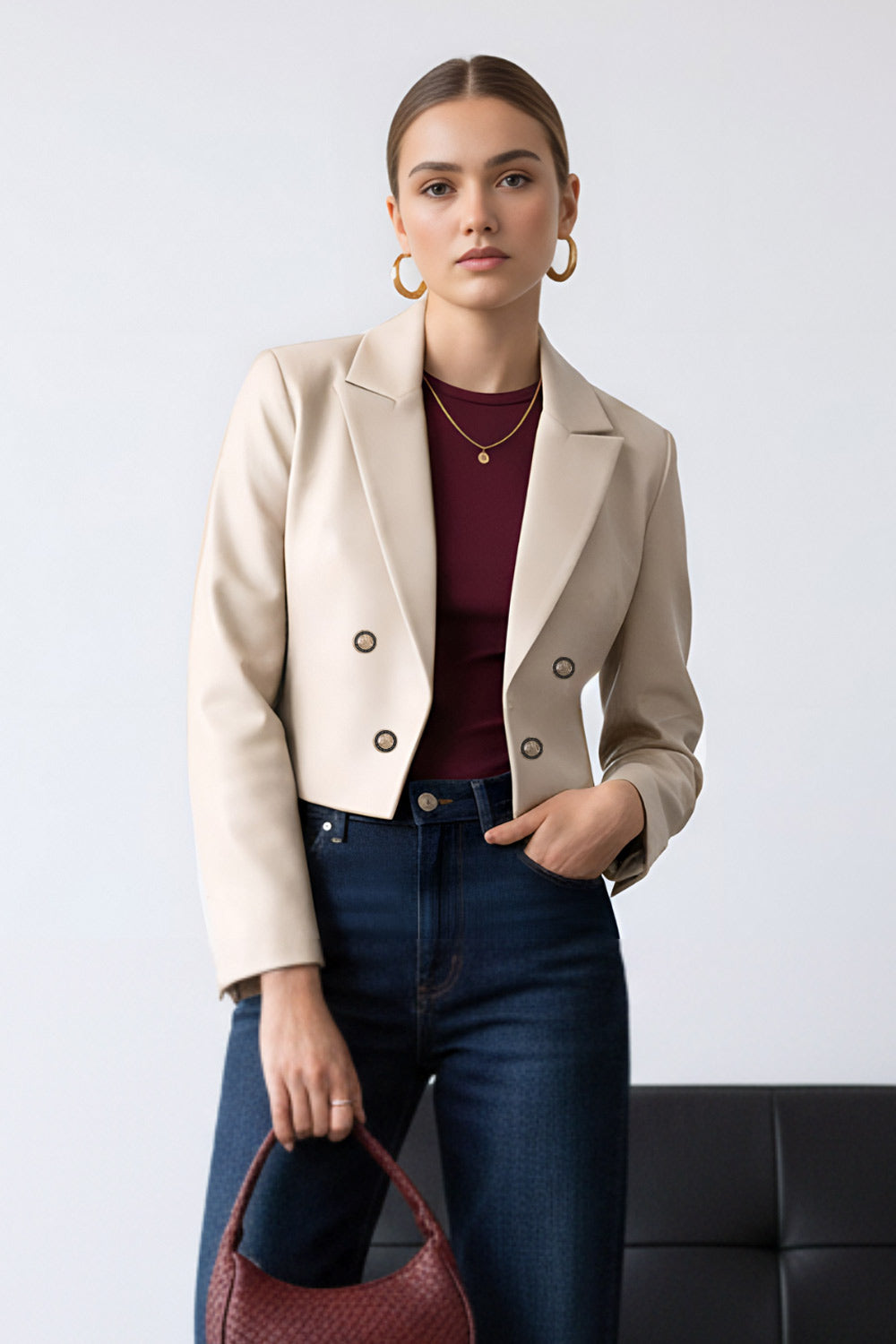 Blazer corto abierto de efecto piel, fit recto, con hombreras y solapa, manga larga y botones decorativos frontales en contraste.