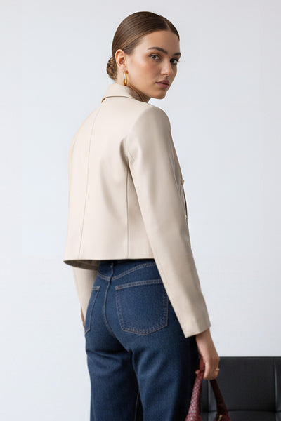 Blazer corto abierto de efecto piel, fit recto, con hombreras y solapa, manga larga y botones decorativos frontales en contraste.