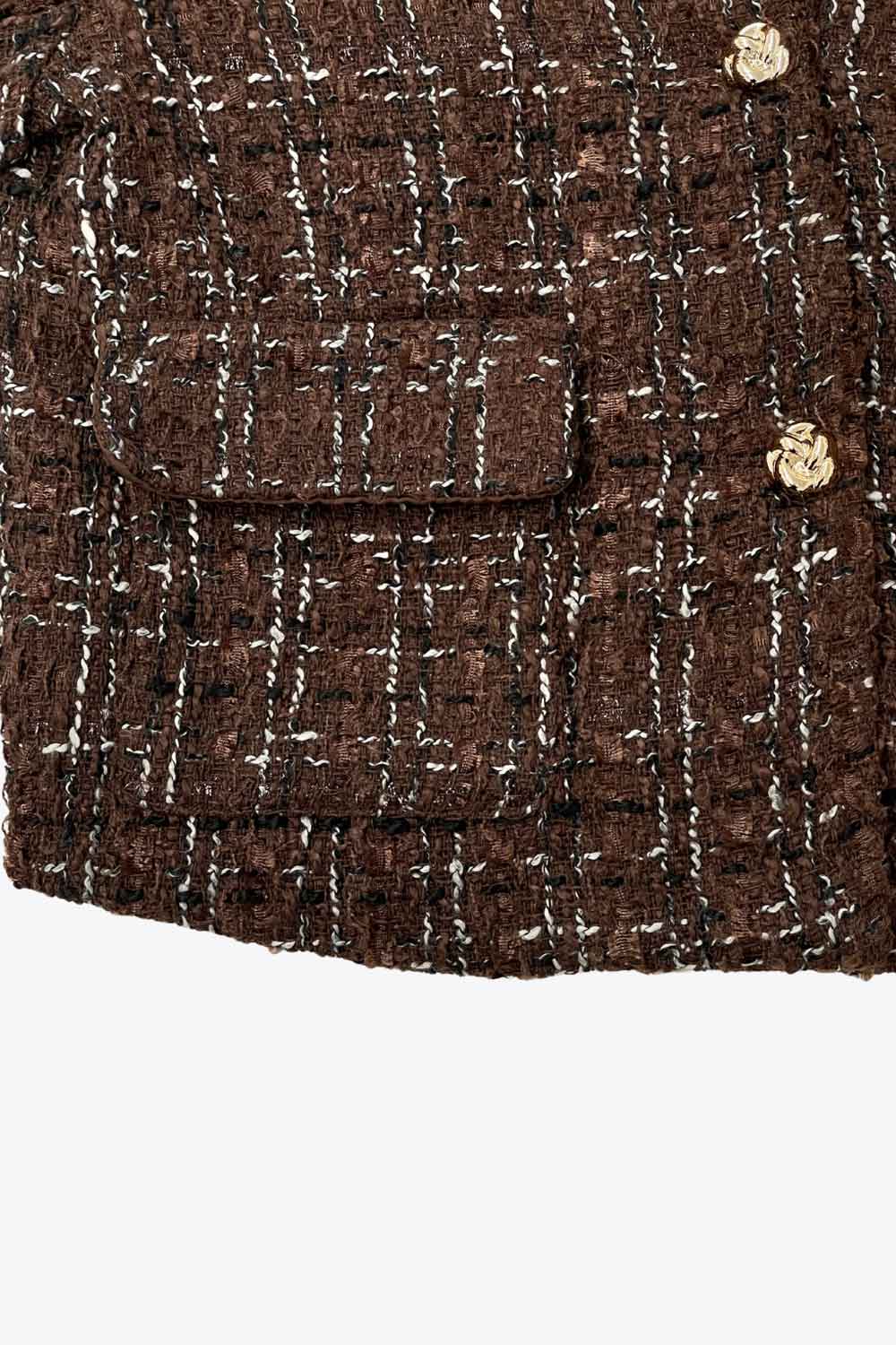 Blazer corto de bouclé, fit recto, con cuello solapa, manga larga, bolsillos delanteros con cartera y cierre frontal con hilera de botones en contraste.