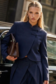 Blazer corto cruzado de manga larga con abertura en puños, cuello mao, vivo decorativo frontal, detalle de botones decorativos frontales y bajo curveado.