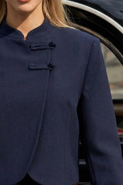 Blazer corto cruzado de manga larga con abertura en puños, cuello mao, vivo decorativo frontal, detalle de botones decorativos frontales y bajo curveado.