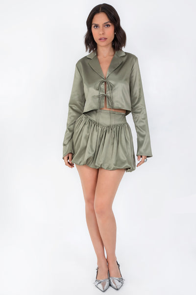 Blazer corto satinado de fit recto, manga larga, con solapa y cierre frontal con doble lazo amarrable.