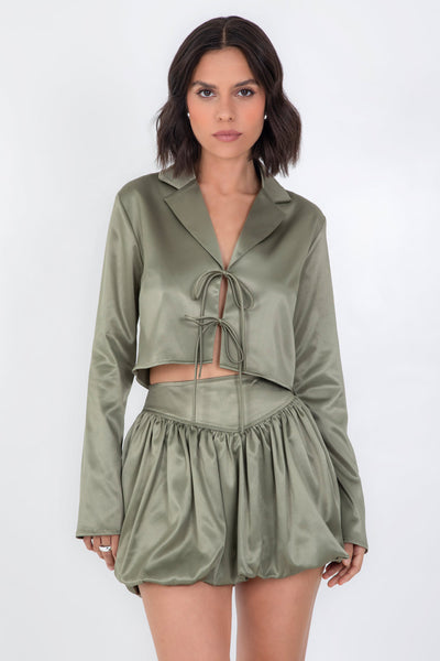 Blazer corto satinado de fit recto, manga larga, con solapa y cierre frontal con doble lazo amarrable.