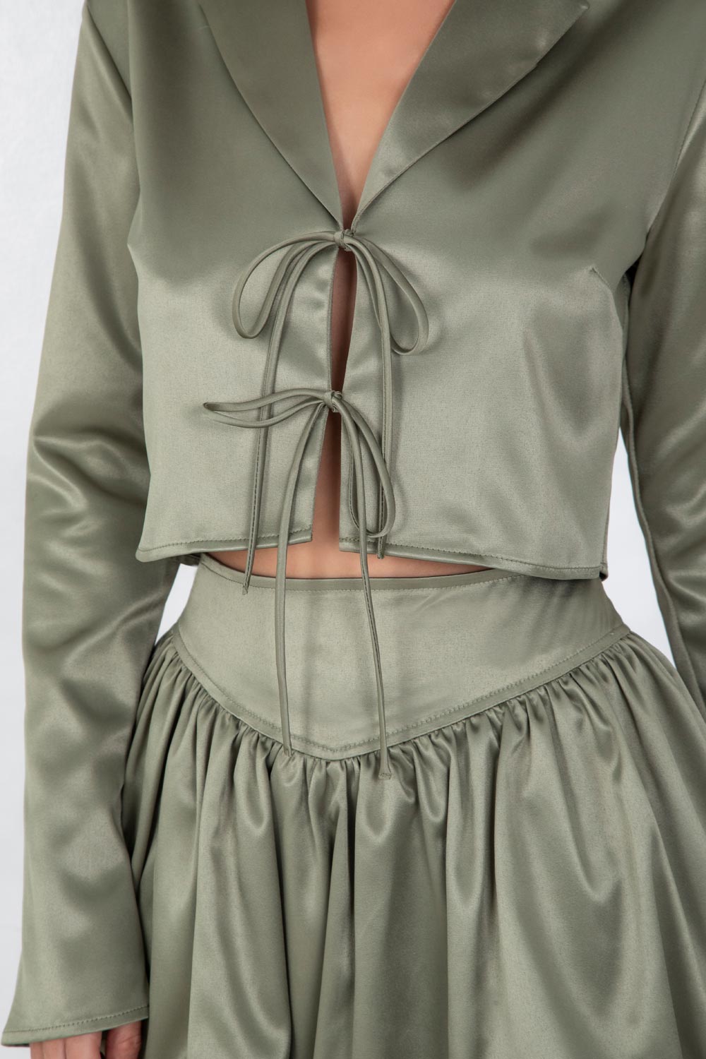 Blazer corto satinado de fit recto, manga larga, con solapa y cierre frontal con doble lazo amarrable.