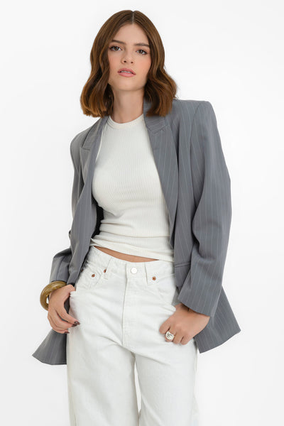 Blazer cruzado de estampado rayas, fit oversized, manga larga, bolsillos delanteros con cartera, con solapa y hombreras. Cierre frontal con cruce de botones en contraste.
