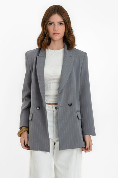 Blazer cruzado de estampado rayas, fit oversized, manga larga, bolsillos delanteros con cartera, con solapa y hombreras. Cierre frontal con cruce de botones en contraste.