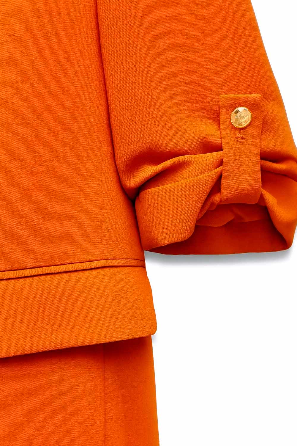 Blazer abierto de fit ligeramente oversized, manga 3/4 rolled up con trabilla decorativa y botón en contraste. Detalle de bolsillos delanteros con cartera.