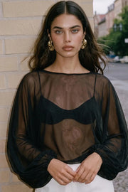 Blusa corta traslúcida de fit fluido, cuello barco y manga larga abullonada con rib elástico en puños.