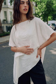 Blusa asimétrica de fit fluido, manga seguida con olanes, plisados y capas de olanes decorativos. Detalle de bajo asimétrico y textura en tejido.
