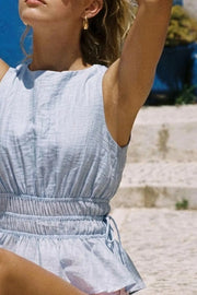 Blusa corta de cuello barco, sin mangas, rib con plisados en cintura, peplum con olanes en bajo y detalle de jaretas ajustables en costados. Cierre posterior con botón y ojal.