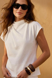 Blusa de cuello alto fluido, plisados en hombros, manga corta seguida y fit recto. Cierre posterior con botón y ojal.