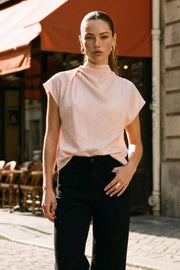 Blusa de cuello alto fluido, plisados en hombro, manga corta seguida y fit recto. Cierre posterior con botón y ojal.