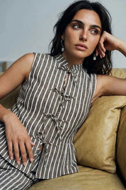Blusa corta de estampado rayas, fit ajustado, cuello mao, sin mangas y cierre frontal con lazos amarrables. Detalle de peplum con olanes en bajo.