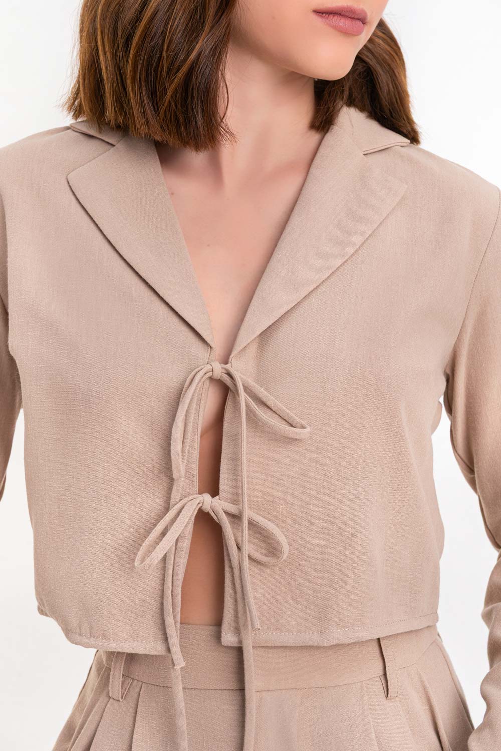 Blusa corta de fit fluido, manga larga, escote v con solapa y cierre frontal con lazos amarrables.