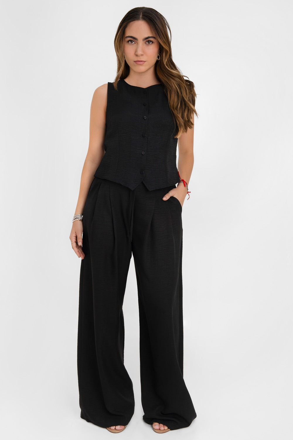 Blusa corta fluida de fit recto, cuello redondo, sin mangas y cierre frontal con hilera de botones. Detalle de abertura frontal en bajo.