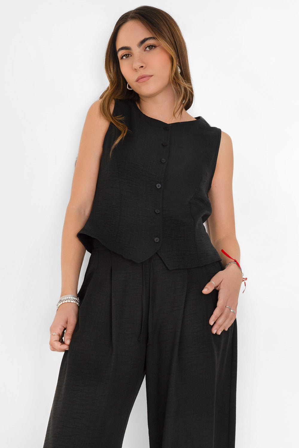 Blusa corta fluida de fit recto, cuello redondo, sin mangas y cierre frontal con hilera de botones. Detalle de abertura frontal en bajo.