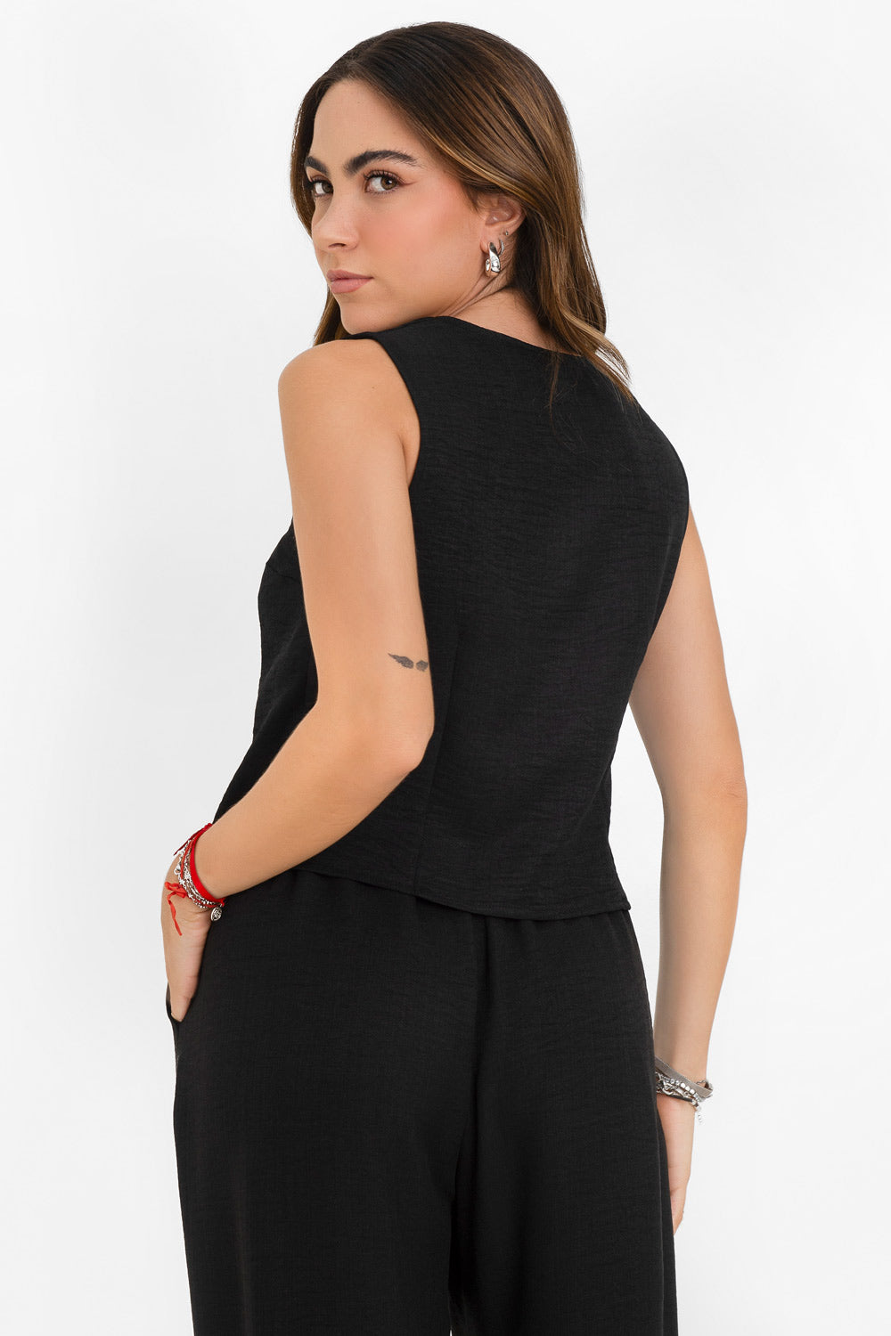 Blusa corta fluida de fit recto, cuello redondo, sin mangas y cierre frontal con hilera de botones. Detalle de abertura frontal en bajo.