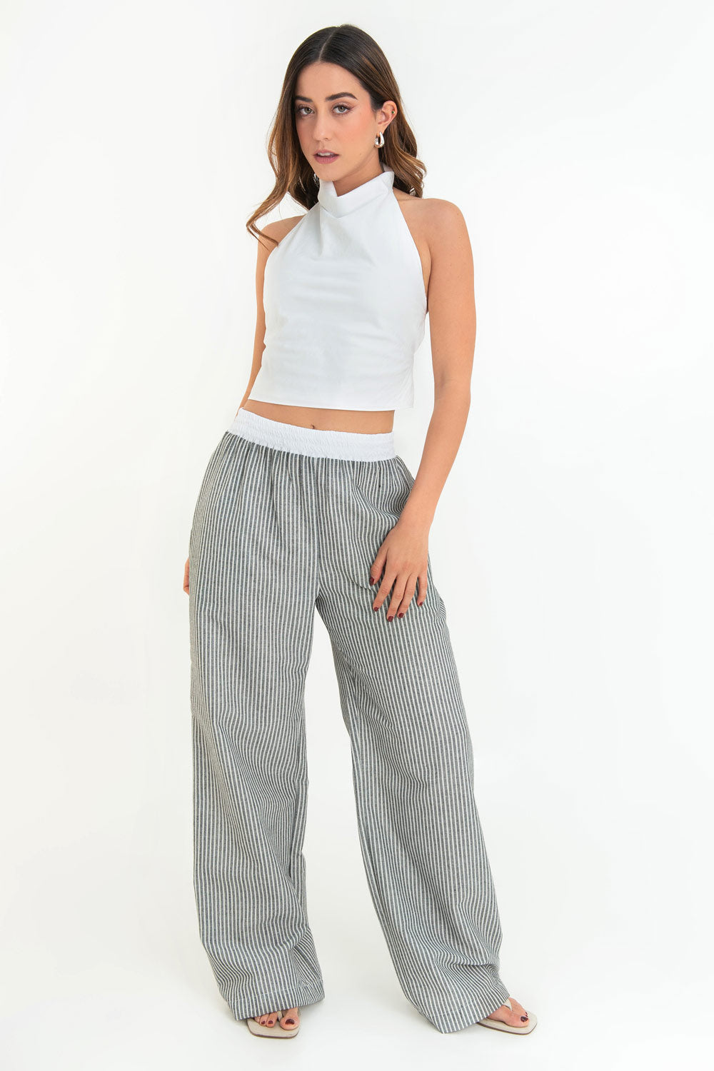 Blusa corta de cuello halter con escote fluido, sin mangas escote en espalda y cierre posterior con botón y ojal.