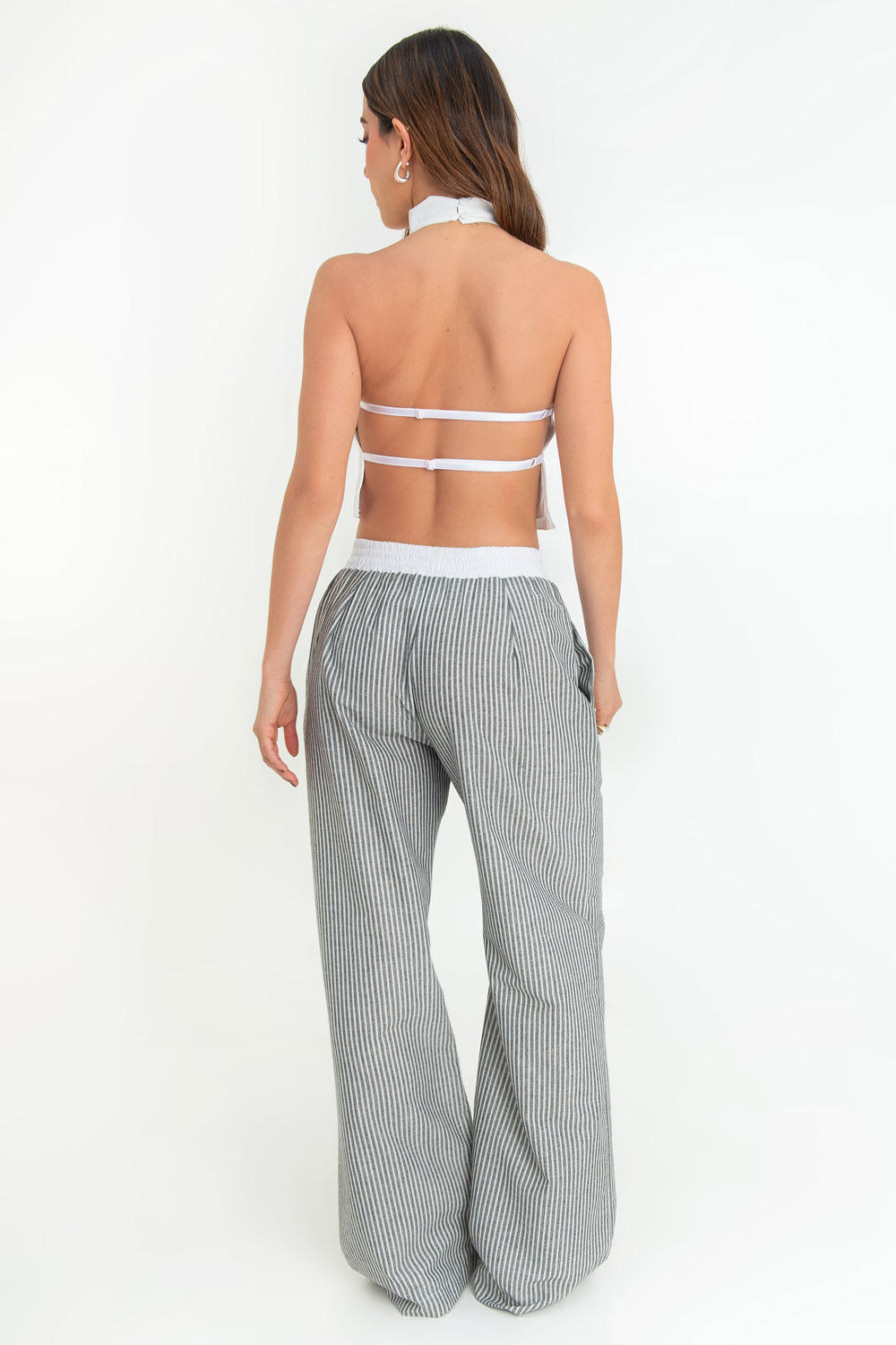 Blusa corta de cuello halter con escote fluido, sin mangas escote en espalda y cierre posterior con botón y ojal.