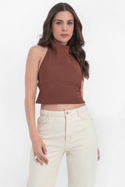 Blusa corta de cuello halter con escote fluido, sin mangas y escote en espalda con tirantes delgados ajustables. Cierre posterior con botón y ojal.