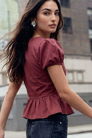 Blusa corta de fit recto, manga corta abullonada con rib elástico en bordes, escote v, peplum con olanes y cierre frontal con hilera de botones en contraste.