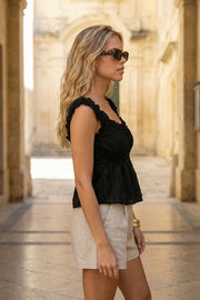 Blusa corta de escote v redondeado y manga corta con rib elástico y olanes en borde, elástico en cintura, peplum con olanes en bajo y detalle de textura en tejido.