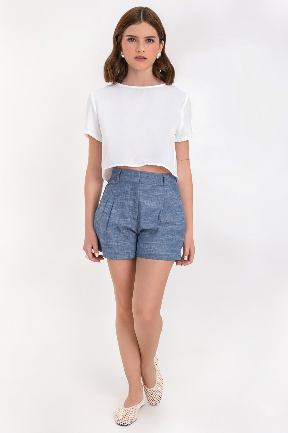 Blusa corta de fit ligeramente oversized, de cuello redondo, manga corta y cierre posterior con botón y ojal.